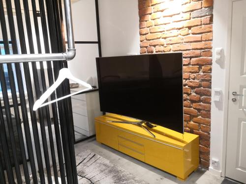 TV de pantalla plana en la parte superior de una cómoda amarilla en Central Ojakatu en Tampere