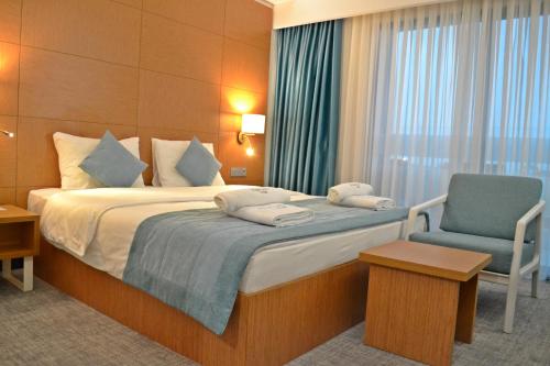 Burhaniye的住宿－TEZMADRA HOTEL，配有一张床和一把椅子的酒店客房