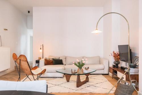 a living room with a white couch and a table at Traditional chic, High Ceilings' apt Aircos and Garage in Antwerp