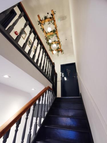 a staircase in a house with a black door and a chandelier at Flamingo Lodge in Torquay