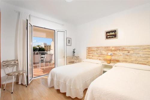 a hotel room with two beds and a balcony at MARCOS Apt in Port de Pollensa