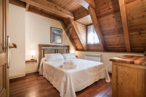 a bedroom with a bed in a room with wooden ceilings at Casa Marimanha by SeaMount Rentals in Salardú