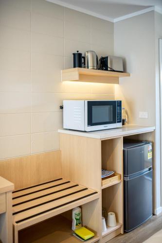 a small kitchen with a microwave on a shelf at Takapuna International Motor Lodge in Auckland