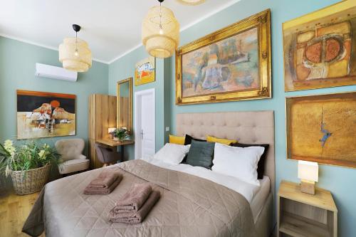 a bedroom with a large bed with paintings on the walls at Kalina Apartments in Brno