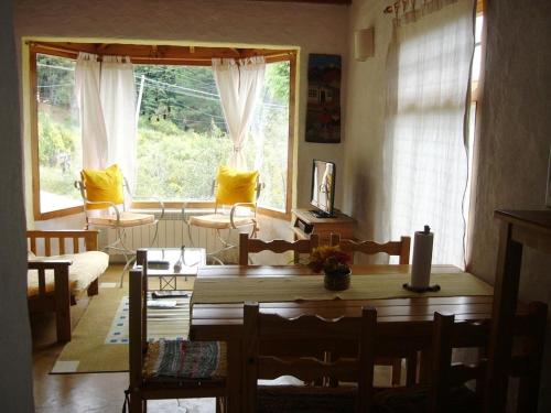 un soggiorno con tavolo, sedie e finestra di Verde Sol a San Carlos de Bariloche