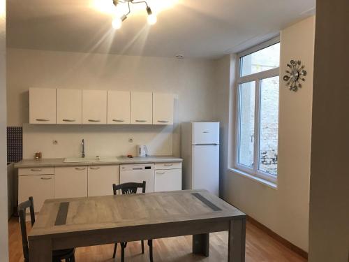 Il comprend une cuisine équipée d'une table et d'un réfrigérateur. dans l'établissement Centr’Appart., à Saint-Omer