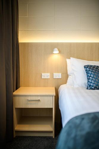 a hotel room with a bed and a nightstand with a bed sidx sidx sidx at Takapuna International Motor Lodge in Auckland