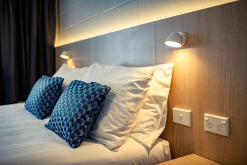 a bed with two blue pillows on top of it at Takapuna International Motor Lodge in Auckland