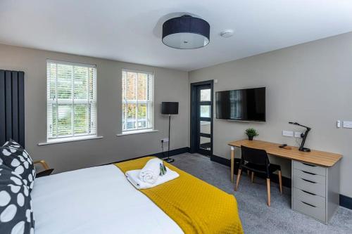 a bedroom with a bed and a desk and a television at BOOTique House - Luxury Group Accommodation in Wakefield in Wakefield