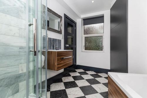 a bathroom with a glass shower and a checkered floor at BOOTique House - Luxury Group Accommodation in Wakefield in Wakefield