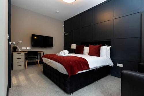 a bedroom with a large bed with a large black headboard at BOOTique House - Luxury Group Accommodation in Wakefield in Wakefield
