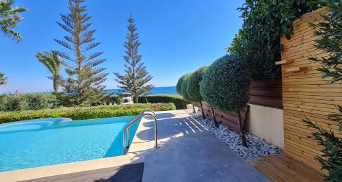 a swimming pool in a yard with trees and bushes at Villa del Mar in Mazotos