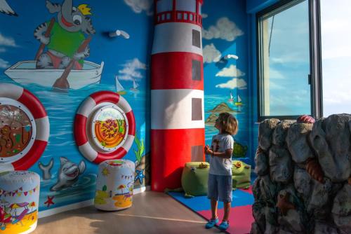 a child standing next to a lighthouse mural in a room at UNAHOTELS Imperial Sport Hotel in Pesaro