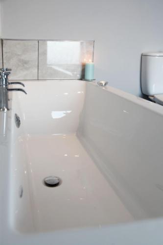 a white bath tub with a sink in a bathroom at The Windmill Inn - Whitby in Whitby