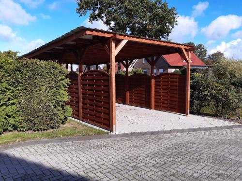 een houten prieel met een paviljoen in een park bij Helgas Ferienwohnung 4 Sterne in Südbrookmerland