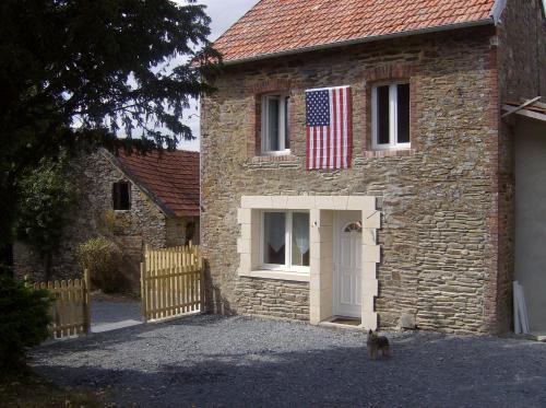 a cat standing outside of a brick house with an american flag at Gîte des Forges in Saint Lo