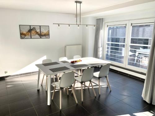 a dining room with a white table and chairs at Vakantieappartement Emiel Centrum Oostende met garage in Ostend