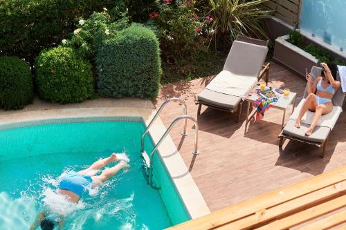 two people are swimming in a swimming pool at Alexandra Golden Boutique Hotel-Adults Only in Chrysi Ammoudia
