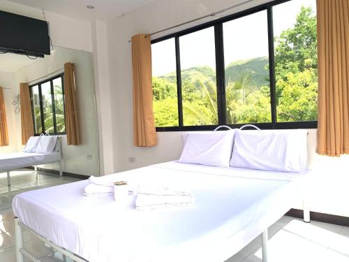 a white bed in a room with a large window at Luna Oslob Travellers Inn in Oslob