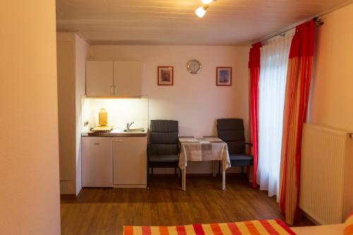 a room with a table and chairs and a kitchen at Gästehaus Steuer in Kröv