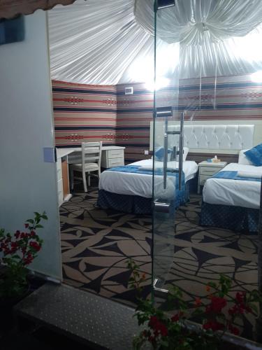 a bedroom with two beds and a glass wall at The Rock Camp Petra in Wadi Musa