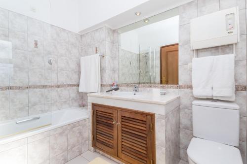 a bathroom with a sink and a tub and a toilet at Peaceful 4BR villa on Gramacho golf resort w/ private pool in Lagoa