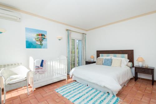 um quarto branco com uma cama e uma cadeira em Peaceful 4BR villa on Gramacho golf resort w/ private pool em Lagoa