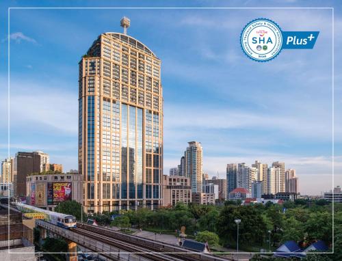 a tall building in front of a city at Emporium Suites by Chatrium in Bangkok