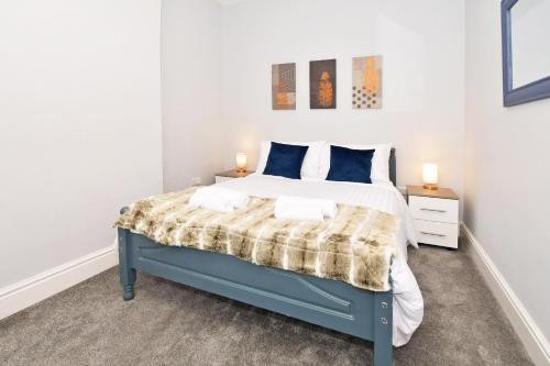 a bedroom with a blue bed with two night stands at Book Somerville House - Stylish Family Home from Home in Crewe