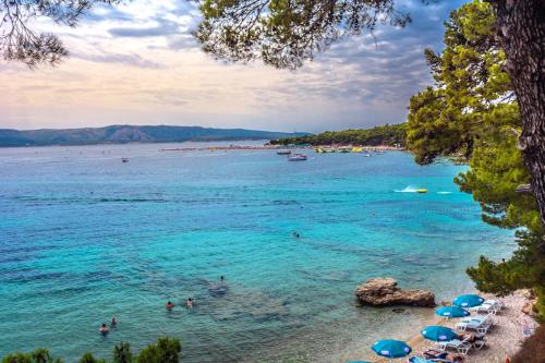 a beach with people in the water and umbrellas at Bluesun Holiday Village Bonaca - Full Board Plus in Bol