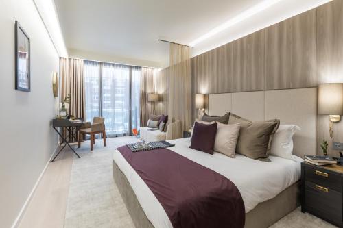 una camera d'albergo con un grande letto e una scrivania di The Quarters Swiss Cottage a Londra