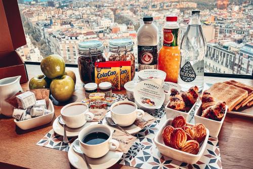 Una mesa cubierta con tazas de café y comida para el desayuno. en Enjoybcn Miro Apartments, en Barcelona