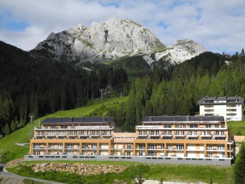 a large building with a mountain in the background at Appartements Nassfeld LUX in Sonnenalpe Nassfeld