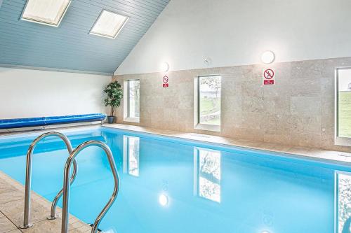 a swimming pool with blue water in a building at Haddon Grove Farm Cottages in Bakewell