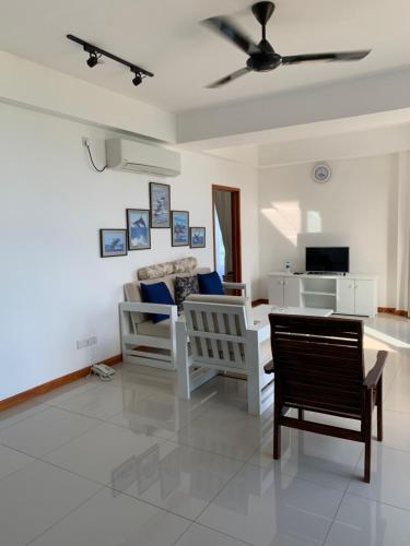 a living room with chairs and a ceiling fan at Nilaveli Beach Apartment Sri Lanka in Nilaveli