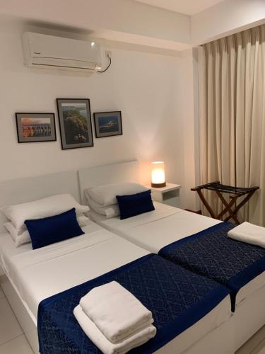 a bedroom with two beds with blue and white sheets at Nilaveli Beach Apartment Sri Lanka in Nilaveli
