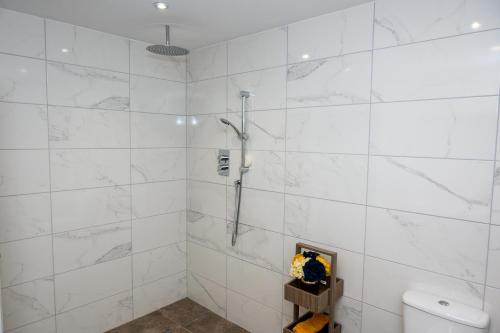 a white tiled bathroom with a shower and a toilet at Weston Lawns Lodges in Bulkington