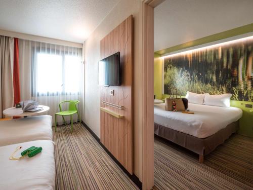 ラベージュにあるIbis Styles Toulouse Labègeのベッド2台とテレビが備わるホテルルームです。