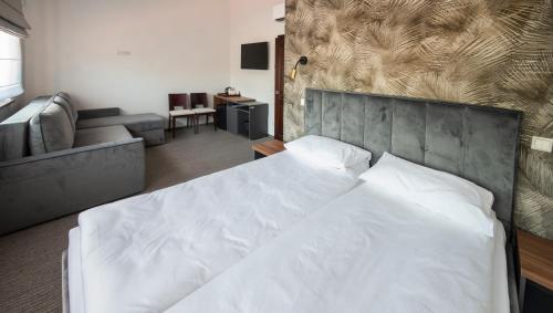a bedroom with a large white bed and a couch at Venckai Venckuose in Venckai
