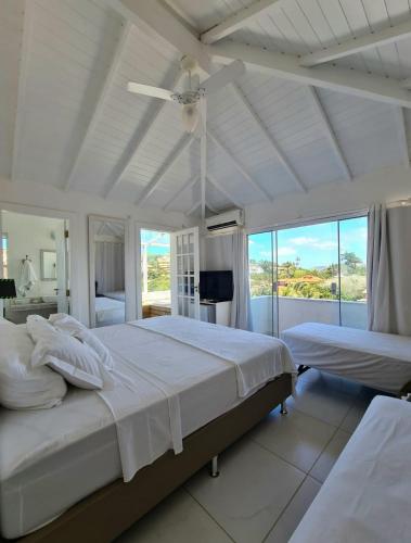 a white bedroom with two beds and a ceiling fan at Pousada Solar da Ferradurinha in Búzios