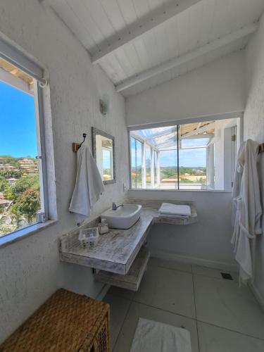 a white bathroom with a sink and a window at Pousada Solar da Ferradurinha in Búzios