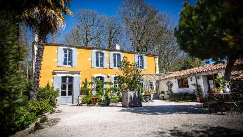 Casa amarilla con ventanas blancas y patio en Chambres d'hôtes La Borderie du Gô près de La Rochelle - Nieul, en Nieul-sur-Mer