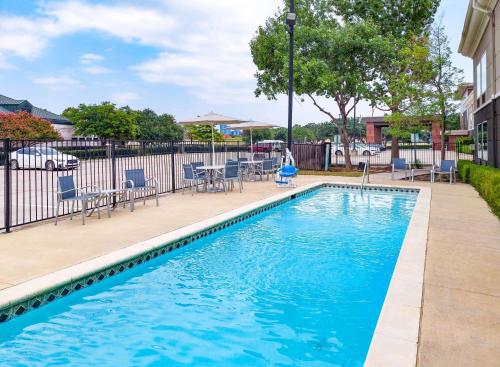 a swimming pool with blue chairs and a fence at La Quinta by Wyndham Dallas - Las Colinas in Irving