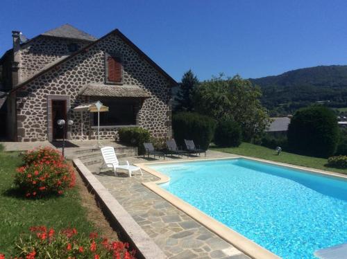 a house with a swimming pool in front of a house at La Grange de Lily in Vic-sur-Cère