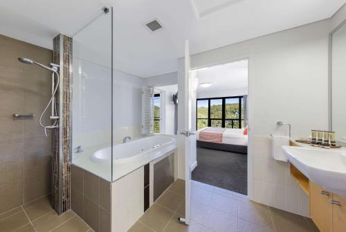 a bathroom with a tub and a shower and a sink at Club Wyndham Coffs Harbour, Trademark Collection by Wyndham in Coffs Harbour
