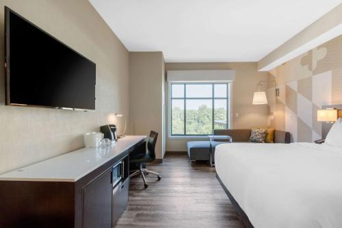 a hotel room with a bed and a flat screen tv at Cambria Hotel College Park in College Park