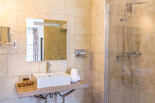 a bathroom with a shower, sink, and mirror at Best Western Marquis de la Baume in Nîmes