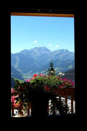 a view of a mountain from a window with flowers at Hôtel La Ferme du Chozal, Chalet de tradition in Hauteluce