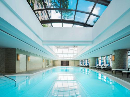 a large swimming pool with a skylight in a building at Swissôtel Grand Shanghai in Shanghai