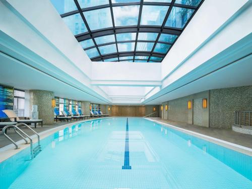 uma grande piscina com tecto de vidro em Swissôtel Grand Shanghai em Xangai